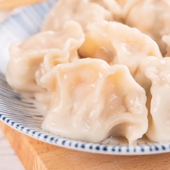 Fresh, delicious boiled pork, shrimp gyoza dumplings on white background with soy sauce and chopsticks, close up, lifestyle. Homemade design concept.