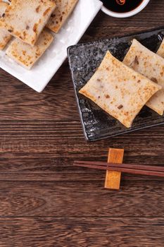 Delicious turnip cake, Chinese traditional radish cake in restaurant with soy sauce for new year's dishes, close up, copy space, top view, flat lay.