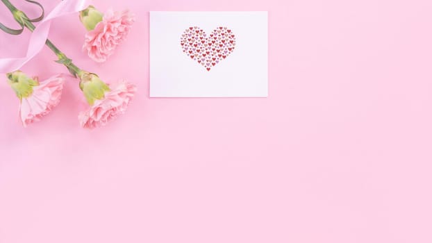 Beautiful, fresh elegant carnation flower bouquet with white greeting thanks gift card isolated on bright pink color background, top view, flat lay concept.