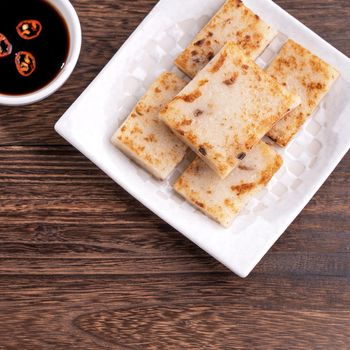 Delicious turnip cake, Chinese traditional radish cake in restaurant with soy sauce for new year's dishes, close up, copy space, top view, flat lay.