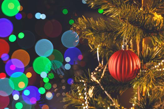 Beautiful Christmas decor concept, bauble hanging on the Christmas tree with sparkling light spot, blurry dark black background, macro detail, close up.