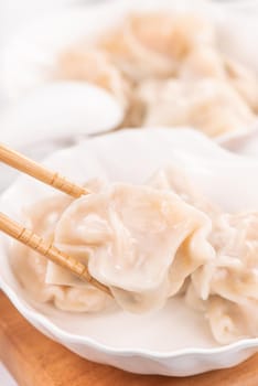 Fresh, delicious boiled pork, shrimp gyoza dumplings on white background with soy sauce and chopsticks, close up, lifestyle. Homemade design concept.