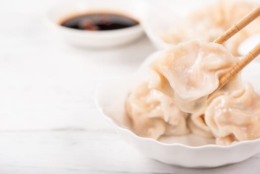 Fresh, delicious boiled pork, shrimp gyoza dumplings on white background with soy sauce and chopsticks, close up, lifestyle. Homemade design concept.