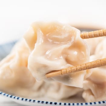 Fresh, delicious boiled pork, shrimp gyoza dumplings on white background with soy sauce and chopsticks, close up, lifestyle. Homemade design concept.