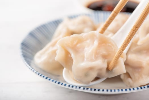 Fresh, delicious boiled pork, shrimp gyoza dumplings on white background with soy sauce and chopsticks, close up, lifestyle. Homemade design concept.