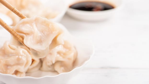 Fresh, delicious boiled pork, shrimp gyoza dumplings on white background with soy sauce and chopsticks, close up, lifestyle. Homemade design concept.