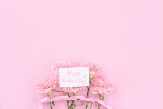 Beautiful, fresh elegant carnation flower bouquet with white greeting thanks gift card isolated on bright pink color background, top view, flat lay concept.