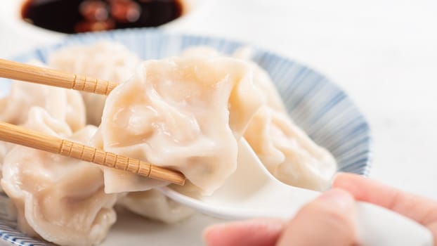 Fresh, delicious boiled pork, shrimp gyoza dumplings on white background with soy sauce and chopsticks, close up, lifestyle. Homemade design concept.