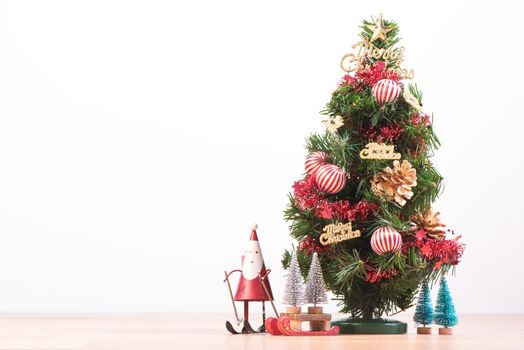 Decorated cute Christmas tree on a wooden floor with white background and toys, blank for festive design concept, close up.