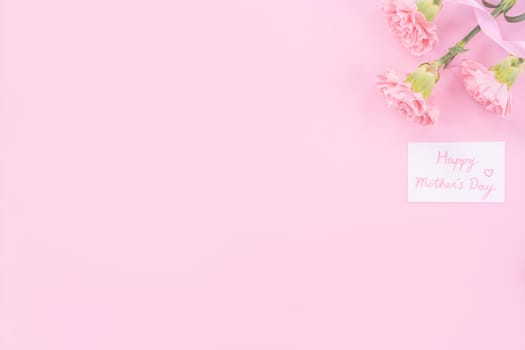 Beautiful, fresh elegant carnation flower bouquet with white greeting thanks gift card isolated on bright pink color background, top view, flat lay concept.