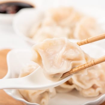 Fresh, delicious boiled pork, shrimp gyoza dumplings on white background with soy sauce and chopsticks, close up, lifestyle. Homemade design concept.