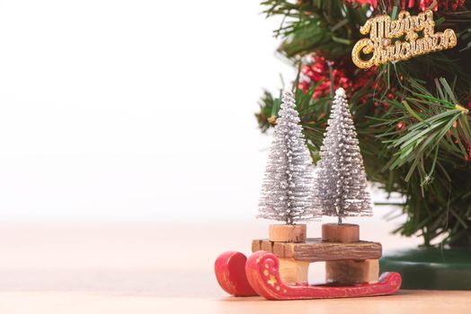 Decorated cute Christmas tree on a wooden floor with white background and toys, blank for festive design concept, close up.