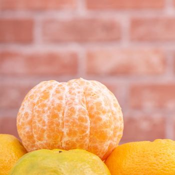 Peeled tangerines in a bamboo sieve basket on dark wooden table with red brick wall background, Chinese lunar new year fruit design concept, close up.