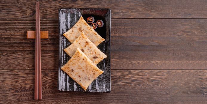Delicious turnip cake, Chinese traditional radish cake in restaurant with soy sauce for new year's dishes, close up, copy space, top view, flat lay.