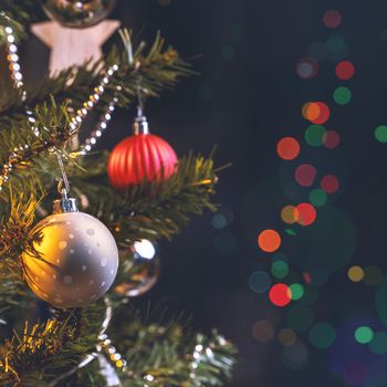 Beautiful Christmas decor concept, bauble hanging on the Christmas tree with sparkling light spot, blurry dark black background, macro detail, close up.