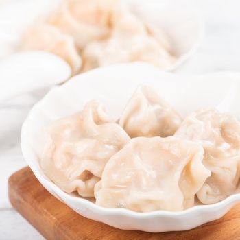 Fresh, delicious boiled pork gyoza dumplings, jiaozi on white background with soy sauce and chopsticks, close up, lifestyle. Homemade design concept.