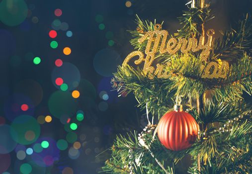 Beautiful Christmas decor concept, bauble hanging on the Christmas tree with sparkling light spot, blurry dark black background, macro detail, close up.