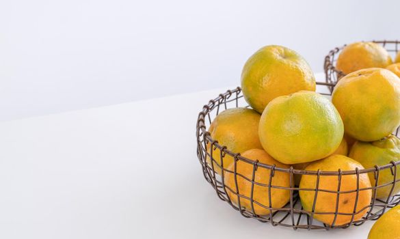 Beautiful peeled tangerines in a plate and metal basket isolated on bright white clean table in a modern contemporary kitchen island, close up.