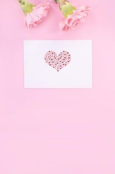 Beautiful, fresh elegant carnation flower bouquet with white greeting thanks gift card isolated on bright pink color background, top view, flat lay concept.