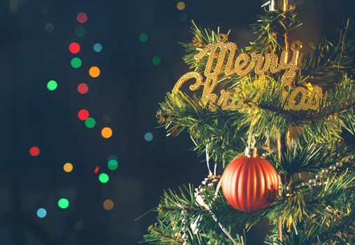 Beautiful Christmas decor concept, bauble hanging on the Christmas tree with sparkling light spot, blurry dark black background, macro detail, close up.