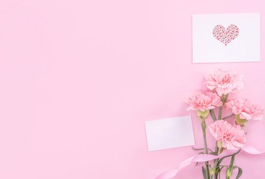 Beautiful, fresh elegant carnation flower bouquet with white greeting thanks gift card isolated on bright pink color background, top view, flat lay concept.