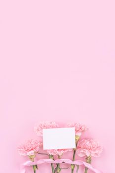 Beautiful, fresh elegant carnation flower bouquet with white greeting thanks gift card isolated on bright pink color background, top view, flat lay concept.