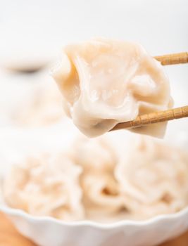 Fresh, delicious boiled pork, shrimp gyoza dumplings on white background with soy sauce and chopsticks, close up, lifestyle. Homemade design concept.