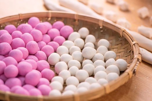 An Asia woman is making Tang yuan, yuan xiao, Chinese traditional food rice dumplings in red and white for lunar new year, winter festival, close up.