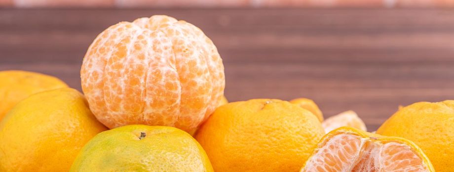 Peeled tangerines in a bamboo sieve basket on dark wooden table with red brick wall background, Chinese lunar new year fruit design concept, close up.