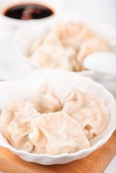 Fresh, delicious boiled pork gyoza dumplings, jiaozi on white background with soy sauce and chopsticks, close up, lifestyle. Homemade design concept.