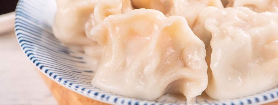 Fresh, delicious boiled pork gyoza dumplings, jiaozi on white background with soy sauce and chopsticks, close up, lifestyle. Homemade design concept.