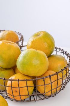 Beautiful peeled tangerines in a plate and metal basket isolated on bright white clean table in a modern contemporary kitchen island, close up.