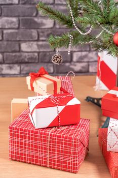 Decorated Christmas tree with wrapped beautiful red and white gifts at home with black brick wall, festive design concept, close up.