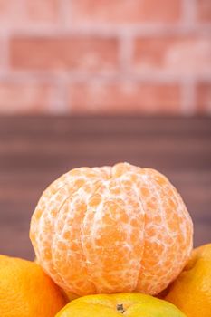 Peeled tangerines in a bamboo sieve basket on dark wooden table with red brick wall background, Chinese lunar new year fruit design concept, close up.