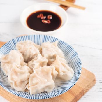 Fresh, delicious boiled pork gyoza dumplings, jiaozi on white background with soy sauce and chopsticks, close up, lifestyle. Homemade design concept.