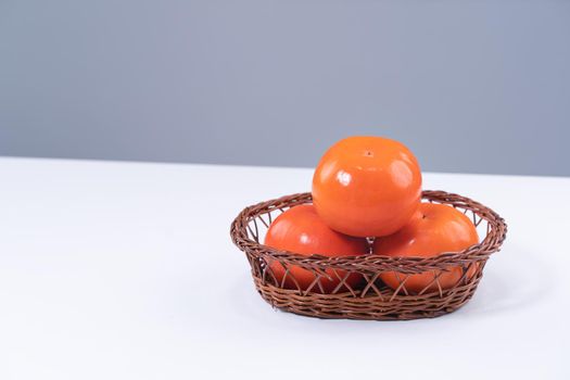 Fresh beautiful sliced sweet persimmon kaki isolated on white kitchen table with gray blue background, Chinese lunar new year design concept, close up.