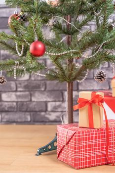 Decorated Christmas tree with wrapped beautiful red and white gifts at home with black brick wall, festive design concept, close up.