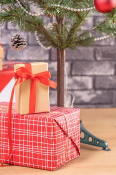 Decorated Christmas tree with wrapped beautiful red and white gifts at home with black brick wall, festive design concept, close up.