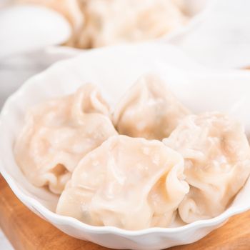 Fresh, delicious boiled pork gyoza dumplings, jiaozi on white background with soy sauce and chopsticks, close up, lifestyle. Homemade design concept.