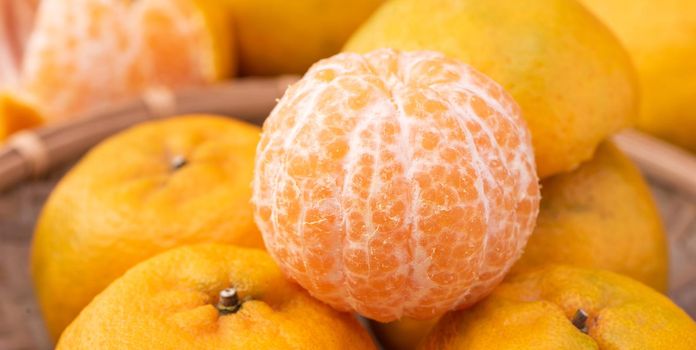 Fresh, beautiful orange color tangerine on bamboo sieve over dark wooden table. Seasonal, traditional fruit of Chinese lunar new year, close up.