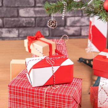 Decorated Christmas tree with wrapped beautiful red and white gifts at home with black brick wall, festive design concept, close up.