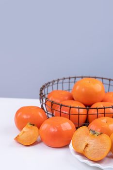 Fresh beautiful sliced sweet persimmon kaki isolated on white kitchen table with gray blue background, Chinese lunar new year design concept, close up.