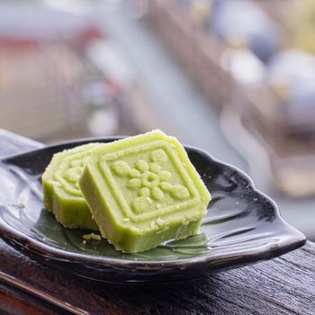 Delicious green mung bean cake with black tea plate on wooden railing of a teahouse in Taiwan with beautiful landscape in background, close up.