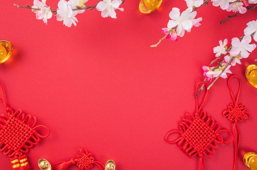 Design concept of Chinese lunar new year - Beautiful Chinese knot with plum blossom isolated on red background, flat lay, top view, overhead layout.