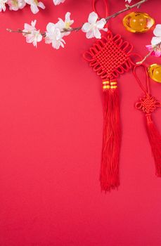 Design concept of Chinese lunar new year - Beautiful Chinese knot with plum blossom isolated on red background, flat lay, top view, overhead layout.