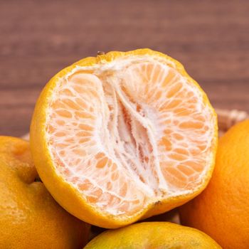 Fresh, beautiful orange color tangerine on bamboo sieve over dark wooden table. Seasonal, traditional fruit of Chinese lunar new year, close up.