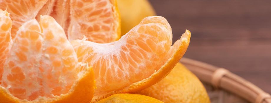 Fresh, beautiful orange color tangerine on bamboo sieve over dark wooden table. Seasonal, traditional fruit of Chinese lunar new year, close up.