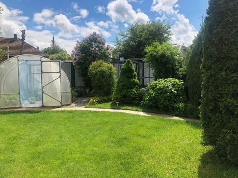 Small Arched greenhouse In garden with a green lawn