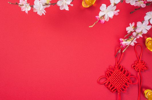 Design concept of Chinese lunar new year - Beautiful Chinese knot with plum blossom isolated on red background, flat lay, top view, overhead layout.