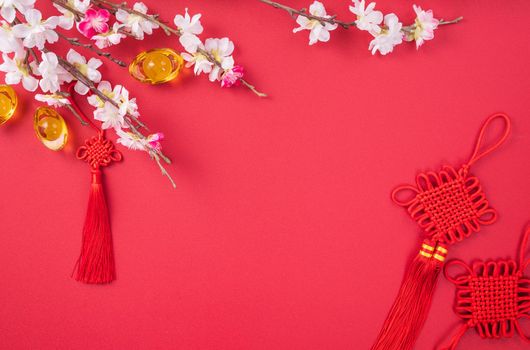 Design concept of Chinese lunar new year - Beautiful Chinese knot with plum blossom isolated on red background, flat lay, top view, overhead layout.